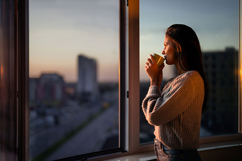 Woman looks out of the window of her home