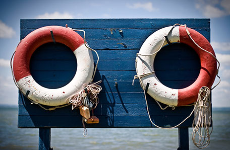 Two old life preservers on a blue board next to a lake